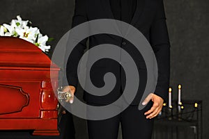 Young man carrying wooden casket in funeral home,