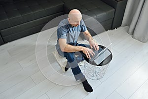 Young man in casual clothes sitting on floor and working on his laptop computer at home. Stay home and work online. Quarantine