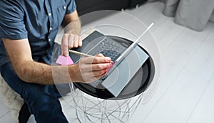 Young man in casual clothes sitting on floor and working on his laptop computer at home. Stay home and work online. Quarantine