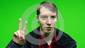 Young man in casual clothing showing victory sign hand on green screen background. Chroma key