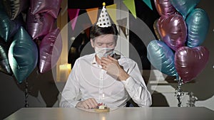 Young man celebrating her birthday alone. Male in protective medical mask