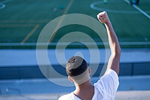 Young man celebrating victory on bleachers watching football