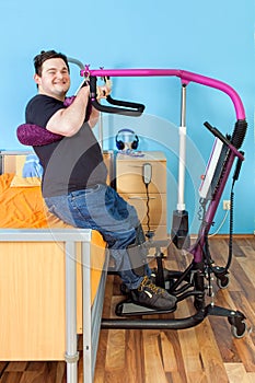 Young man with cerebral palsy using a patient lift.