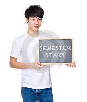 Young man with chalkboard showing phrases of semester start