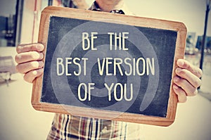 Young man with a chalkboard with the text be the best version of