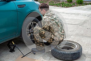 young man changing a car tire for winter tires