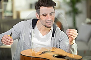 Young man changing guitar strings photo