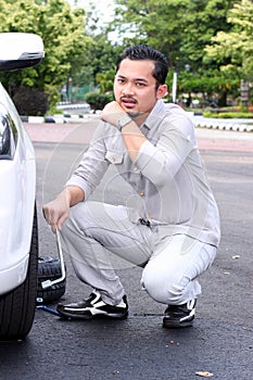 Young man changing the punctured tyre