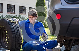 Young man changing wheel on car