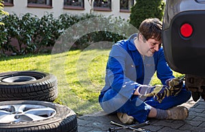 Young man changing wheel on car