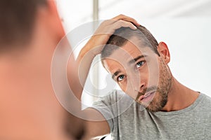 Young man checking hair in mirror