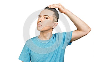 Young man checking hair in mirror, dressed in a blue t shirt, isolated