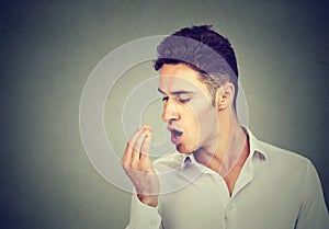 Man checking his breath with hand.