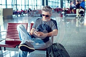 Young man checking his phone while waiting his flight in the air