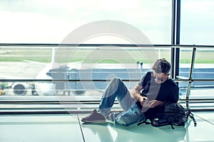 Young man checking his phone while waiting his flight in the air