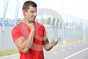 Young man checking  with medical device after training outdoors