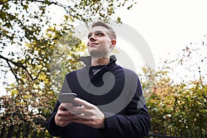 Young Man Checking Messages On Mobile Phone In Oxford Street photo