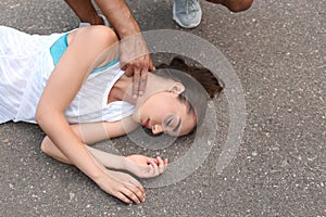 Young man checking pulse of  woman on street