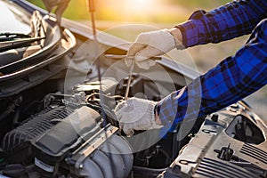 A young man checks his car and repairs it before going on a long journey.