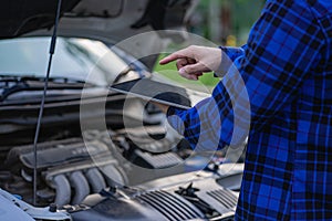 A young man checks his car and repairs it before going on a long journey.