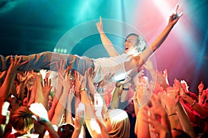 A young man cheering as he crowd surfs at a concert. This concert was created for the sole purpose of this photo shoot