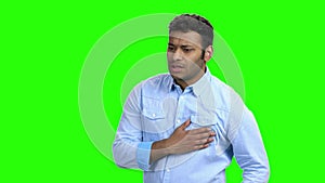 Young man with chest pain on green screen.