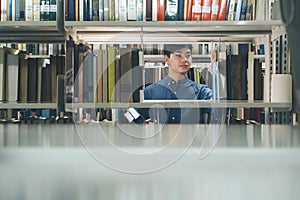 Young man choosing book at public library.