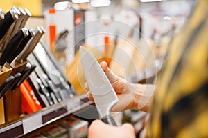 Young man choosing kitchen knife, houseware store