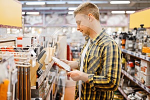 Young man choosing kitchen knife, houseware store