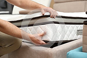 Young man choosing new orthopedic mattress in store