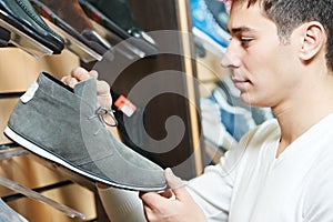 Young man choosing shoe in clothes