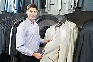 Young man choosing suit in clothes store