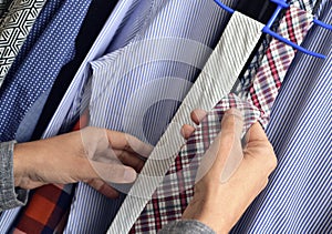 Young man choosing a tie from the closet