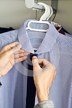 Young man choosing a tie and a shirt from the closet