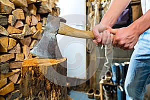 Young man chopping fire wood in mountain chalet