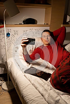 young man in christmas pyjama in bed watching a tablet