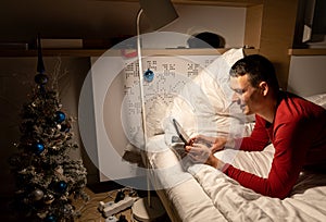 young man in christmas pyjama in bed watching a tablet