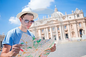 Young man with city map in Vatican city and St. Peter`s Basilica church, Rome. Travel tourist guy on holidays in Europe.