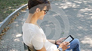Young man in city park using ebook reader