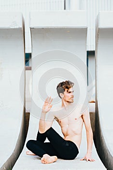 Young man  in the city in the yoga position ardha matsyendrasana stretching and relaxing her body and mind