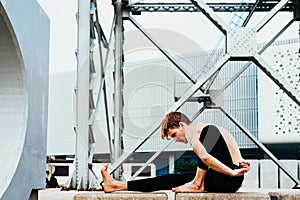 Young man  in the city in the yoga position ardha matsyendrasana stretching and relaxing her body and mind