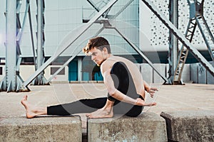 Young man  in the city in the yoga position ardha matsyendrasana stretching and relaxing her body and mind