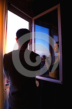 Young man clapping excitedly from the window of his house.