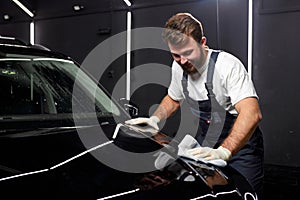 Young man cleaning car with microfiber cloth, car detailing or valeting concept