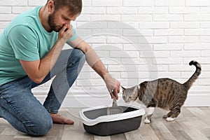 Young man cleaning cat litter tray