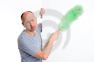 Young man cleaning with feather duster