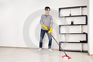 A young man cleaning the floor with a mop