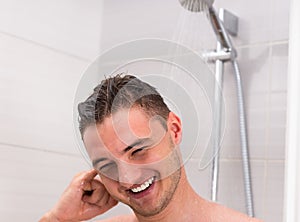 Young man cleaning his ear while taking a shower in the bathroom