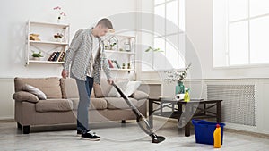 Young man cleaning house with vacuum cleaner