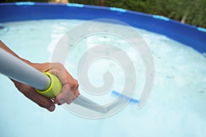 Young man cleaning a portable swimming pool